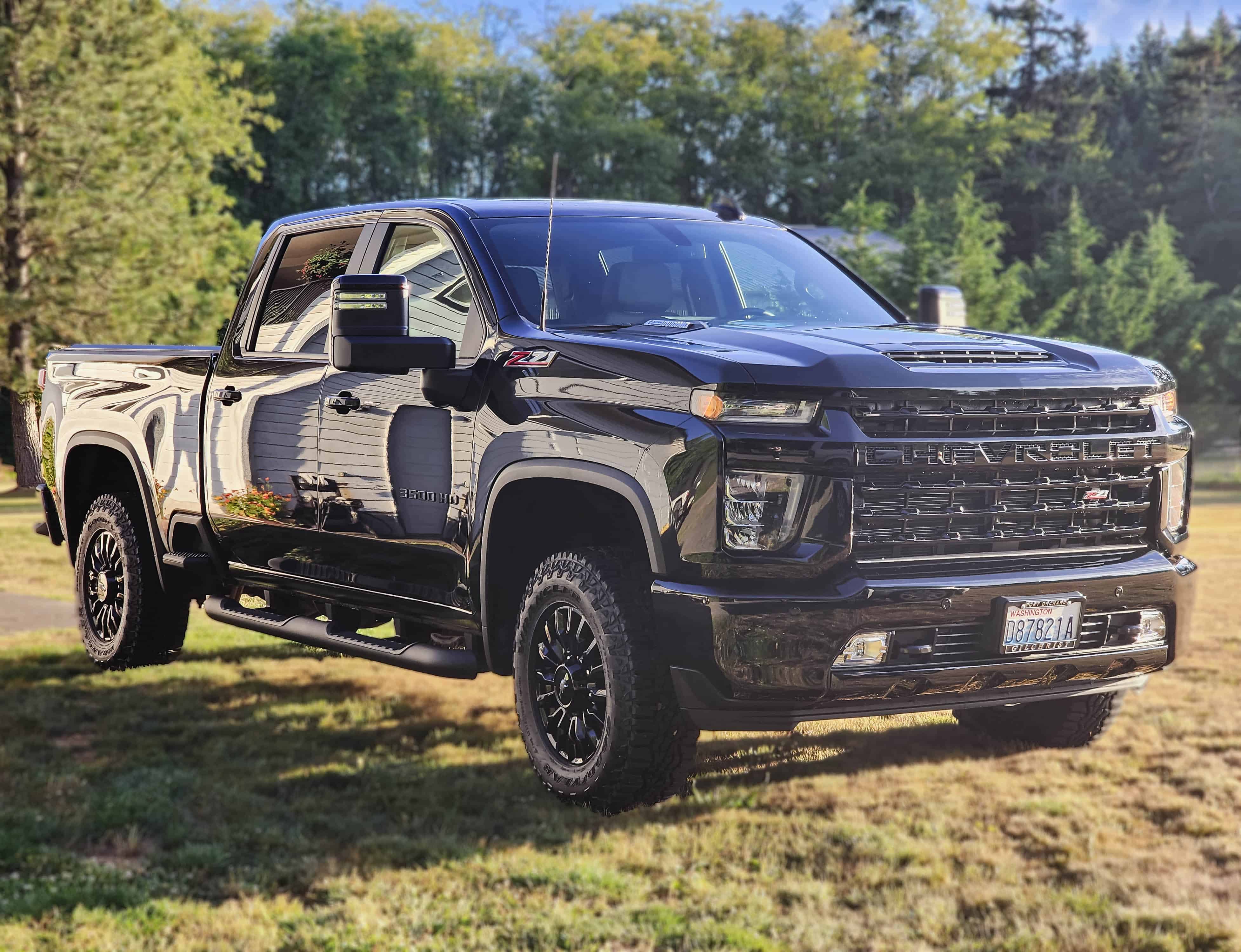 Black Chevrolet Silverado truck showcasing its robust design and off-road tires in a suburban setting.